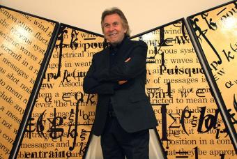 Bernar Venet, posa junto a su obra Trptico dorado con dos saturaciones
