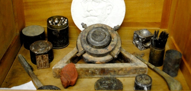 De izda. a dcha. y de detrs a delante: tiles para batir el metal. Modelo de la medalla de Menndez Pidal.  Molde para el batido de metal. Punzn. Anverso Escuela Po.  til para el cincelado de punzones y troqueles. Martillo de cincelador.  Cinceles. Re