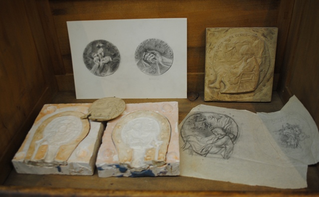 De detrs a delante y de izquierda a derecha:  Proyecto  de medalla (no realizada) para la Asociacin de Crticos de Arte. Anverso y reverso (Mano del Auriga de Delfos) Modelo para hacer reduccin pantogrfica Modelo en polister de la Medalla de la Compl